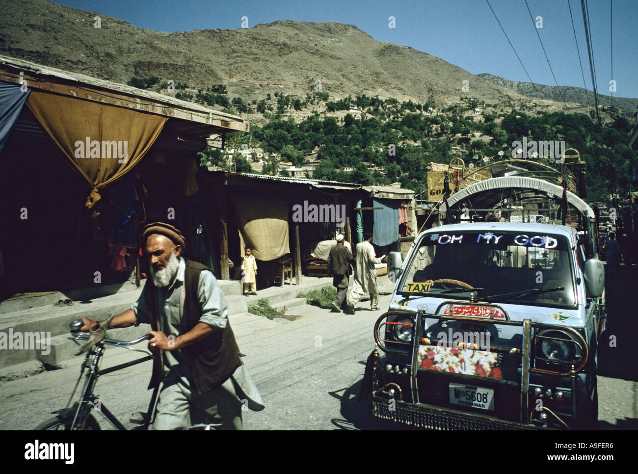 Uomo vecchio con la barba spinge noleggio piccole transporter bus con parole Oh mio Dio sul parabrezza biglietto di frontiera del nord ovest del Pakistan Foto Stock