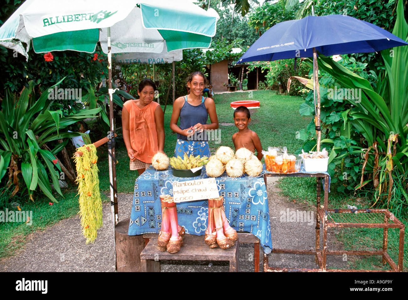 Il tahitiano i bambini per la vendita di frutta in corrispondenza di un lato della strada in stallo sull'isola di Tahiti in Polinesia francese. Foto Stock