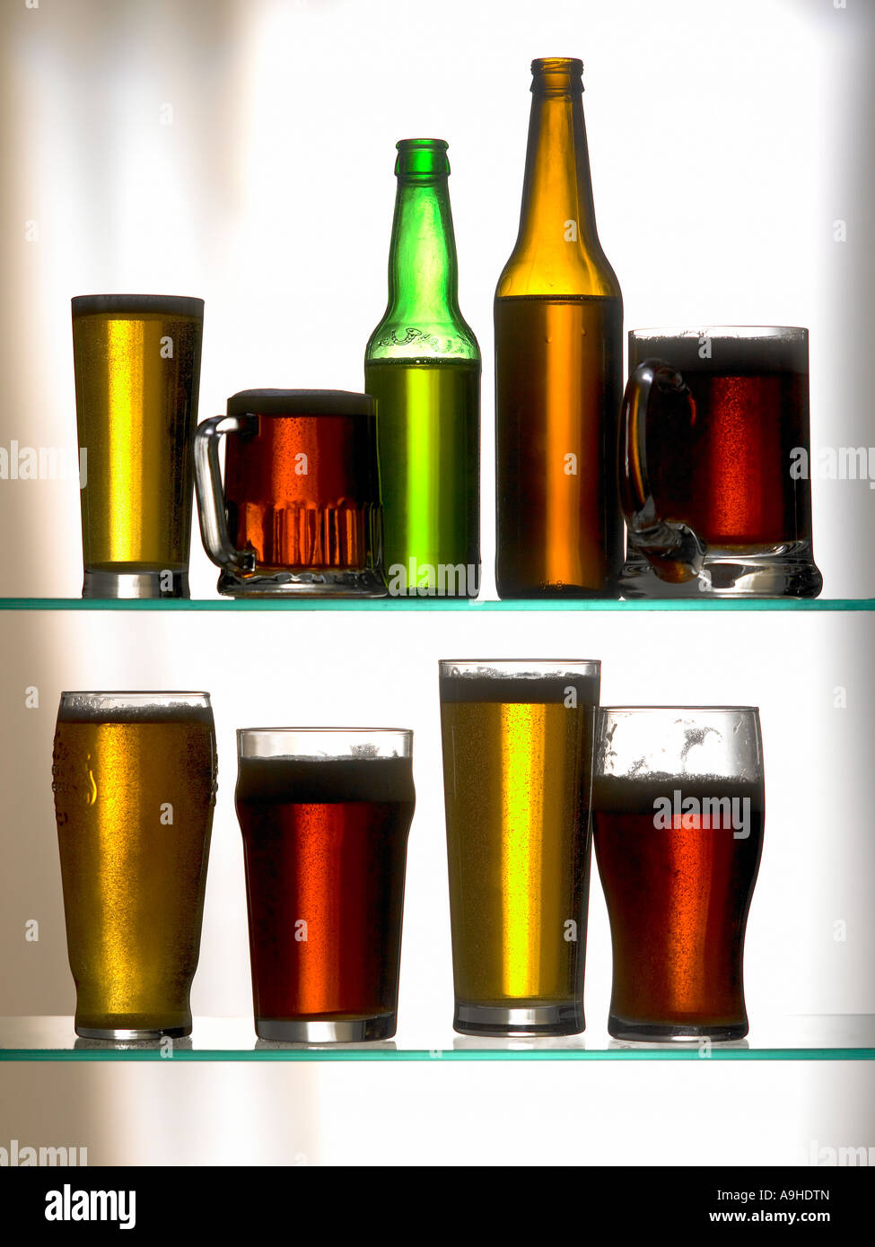 Due file di bottiglie di birra e boccali Foto Stock