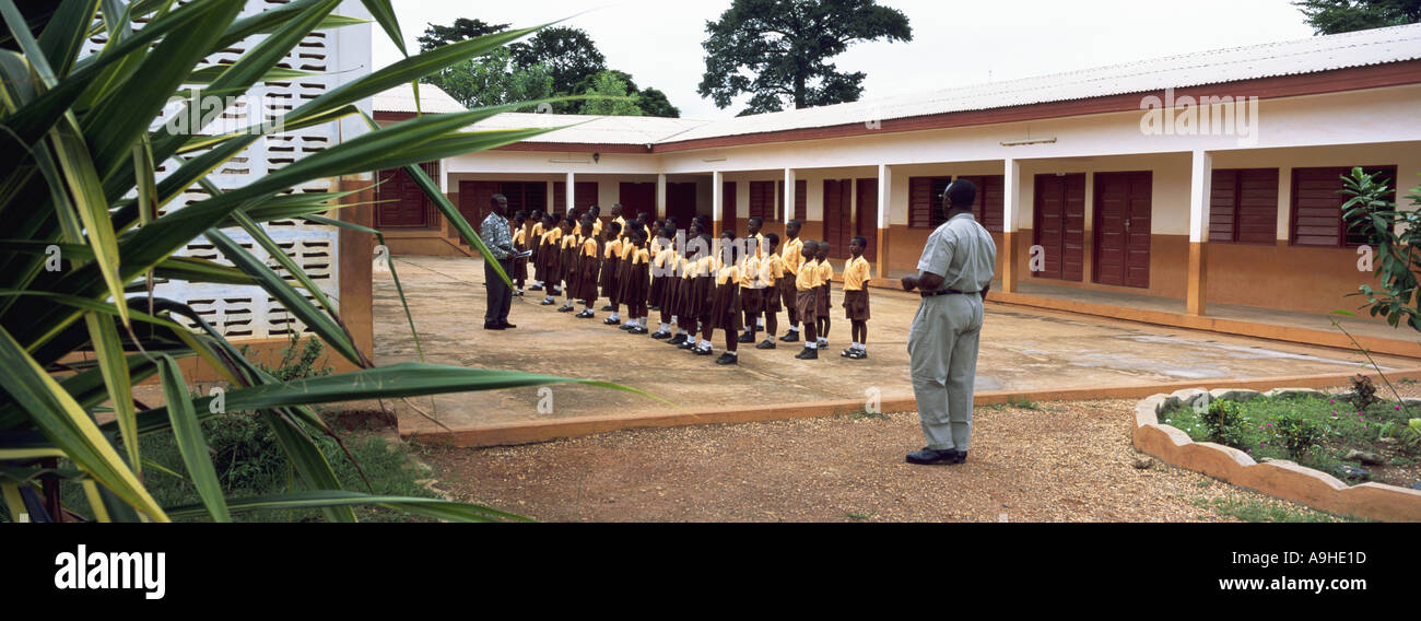 Gli insegnanti e gli alunni si riuniscono al di fuori nel parco giochi per il montaggio alla scuola locale del villaggio di Ashanti regione dell ovest del Ghana Foto Stock