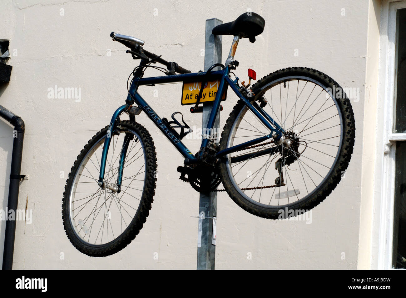 Un Raleigh Mountain bike è fissato sulla parte superiore di un parcheggio  polo di restrizione su una strada della città Foto stock - Alamy