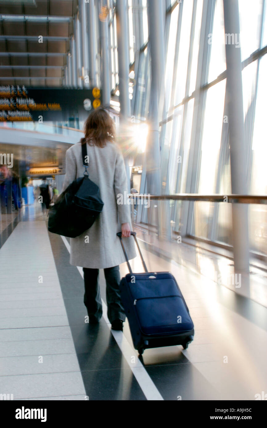 Una donna in aeroporto trascinando i suoi bagagli Foto Stock