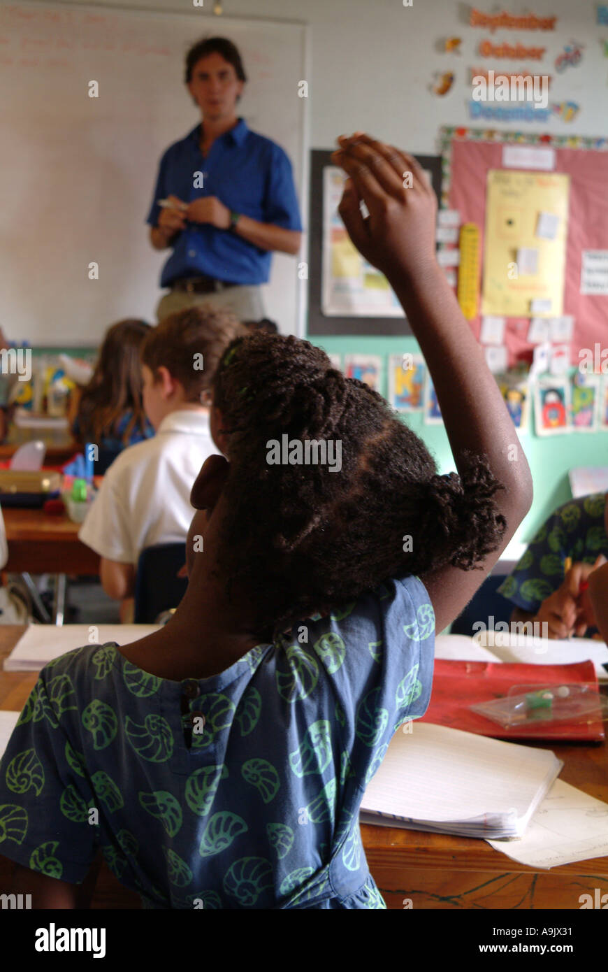 Vista posteriore del schoolgirl con mano sollevata all'interno della classe Foto Stock