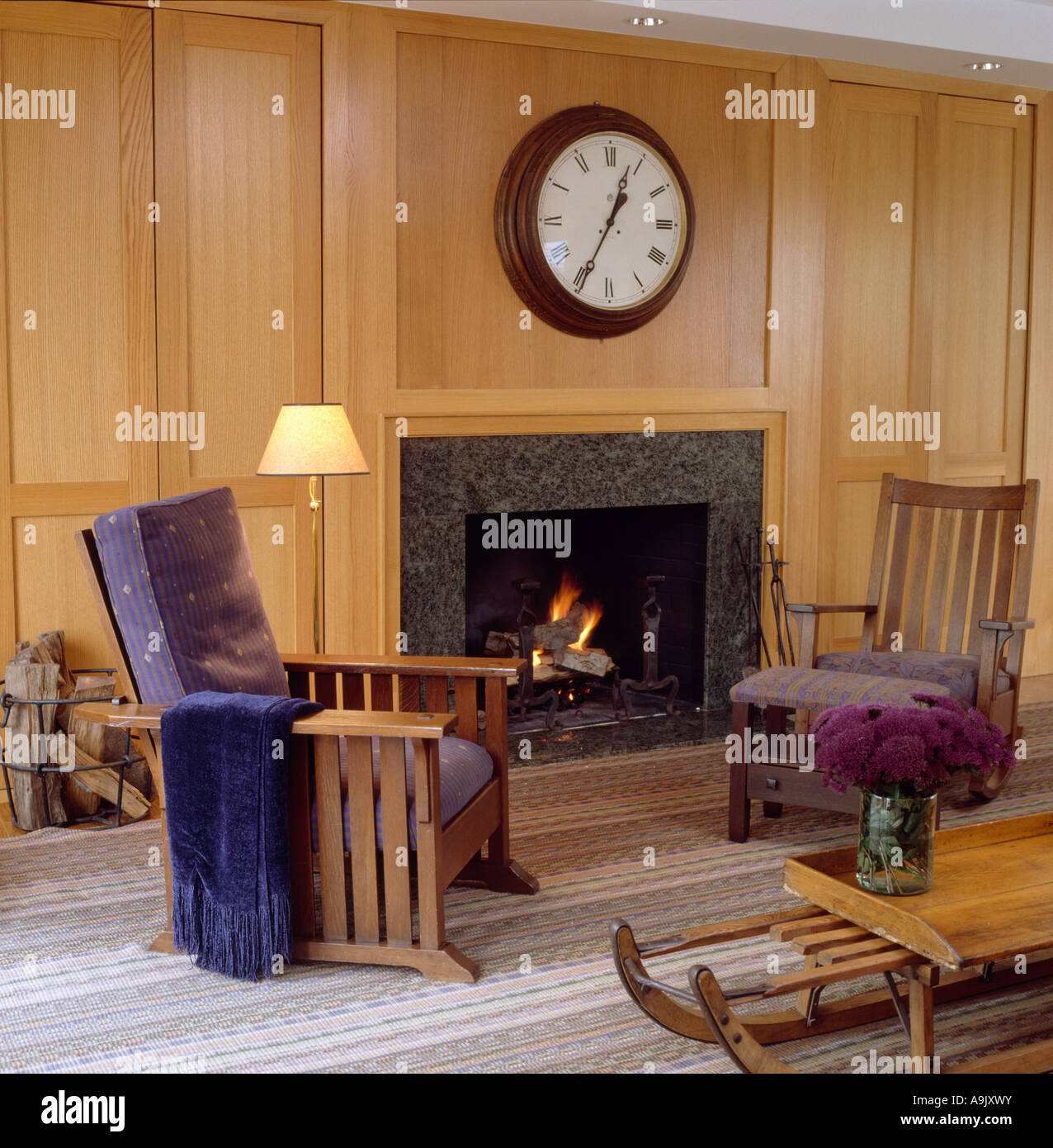 Orologio grande sopra il camino nel soggiorno moderno con pareti in legno e  cuscini blu su poltrone con telai in legno Foto stock - Alamy