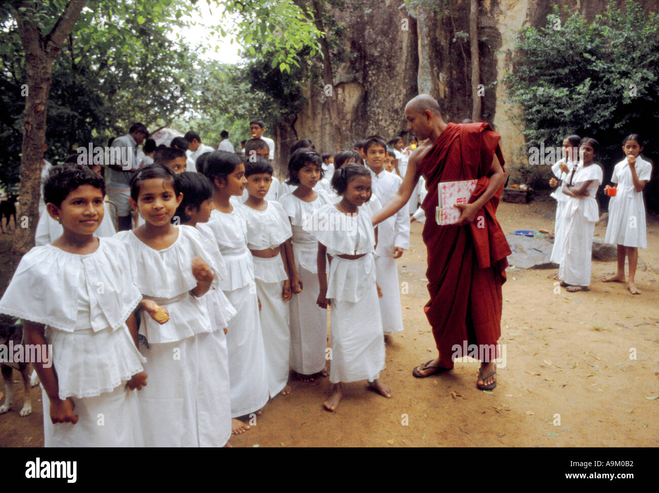 Il monaco senior presso il Buddha Aukana sito nel nord dello Sri Lanka ispeziona alunni uniformi Foto Stock