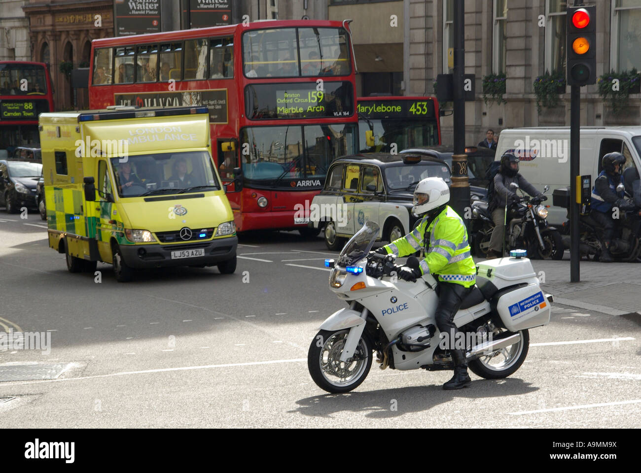 La Metropolitan Police motociclo velocità outrider cop aiuta emergenza NHS autoambulanza sulla carreggiata sbagliata a Trafalgar Square bivio London REGNO UNITO Foto Stock