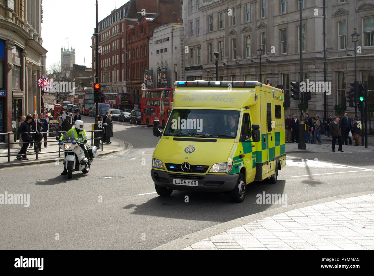 La Metropolitan Police motociclo velocità outrider cop aiuta emergenza NHS autoambulanza sulla carreggiata sbagliata a Trafalgar Square bivio London REGNO UNITO Foto Stock
