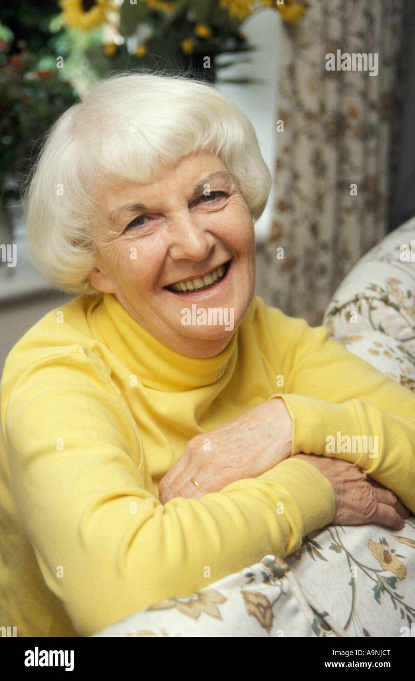 Ritratto felice dai capelli grigi donna matura sporgendoti posteriore del divano Foto Stock