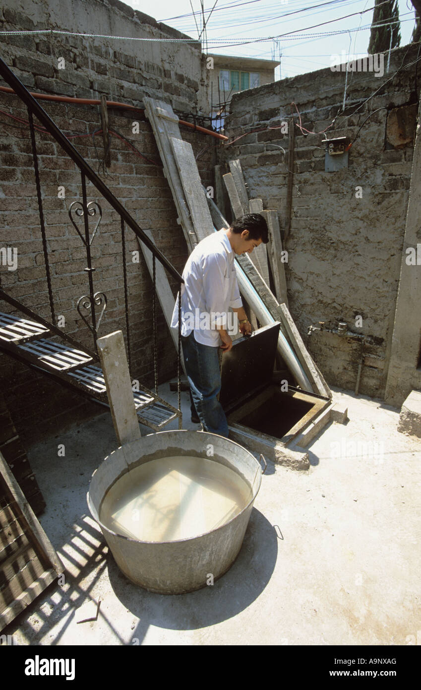 Uomo di raccogliere l'acqua dal pozzetto in Nezahualcoyotl Foto Stock