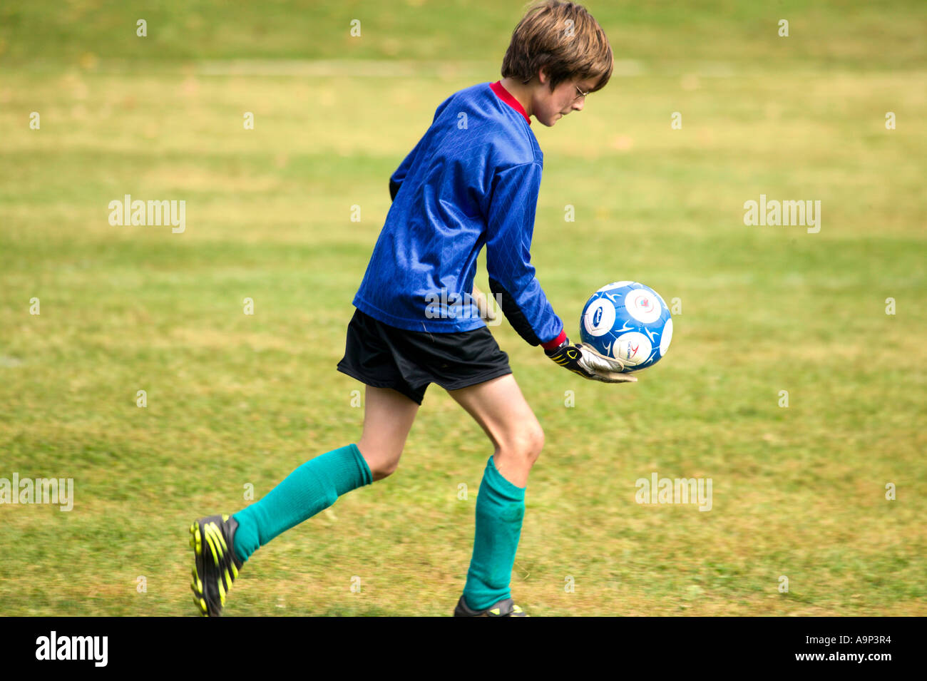 Ragazzo in uniforme che giocano a calcio Foto Stock