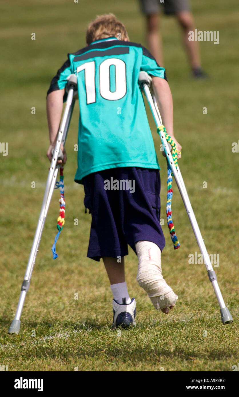 Vista di un ragazzo ferito da dietro. sulle stampelle in sport uniforme. Foto Stock