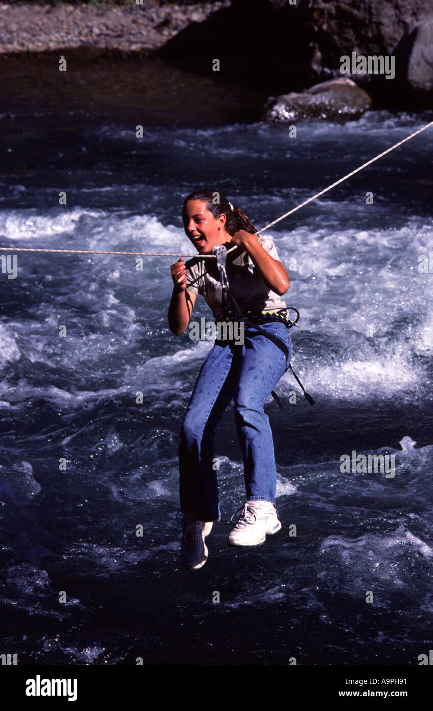 Una giovane ragazza tirando se stessa attraverso una traversa tirolese alto sopra di Shirley Canyon Creek CA Foto Stock