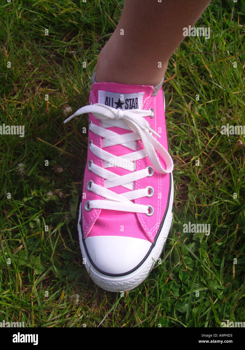 Ragazza s piedi indossando un nuovo paio di rosa scarpe trainer - una scarpa un piede Foto Stock