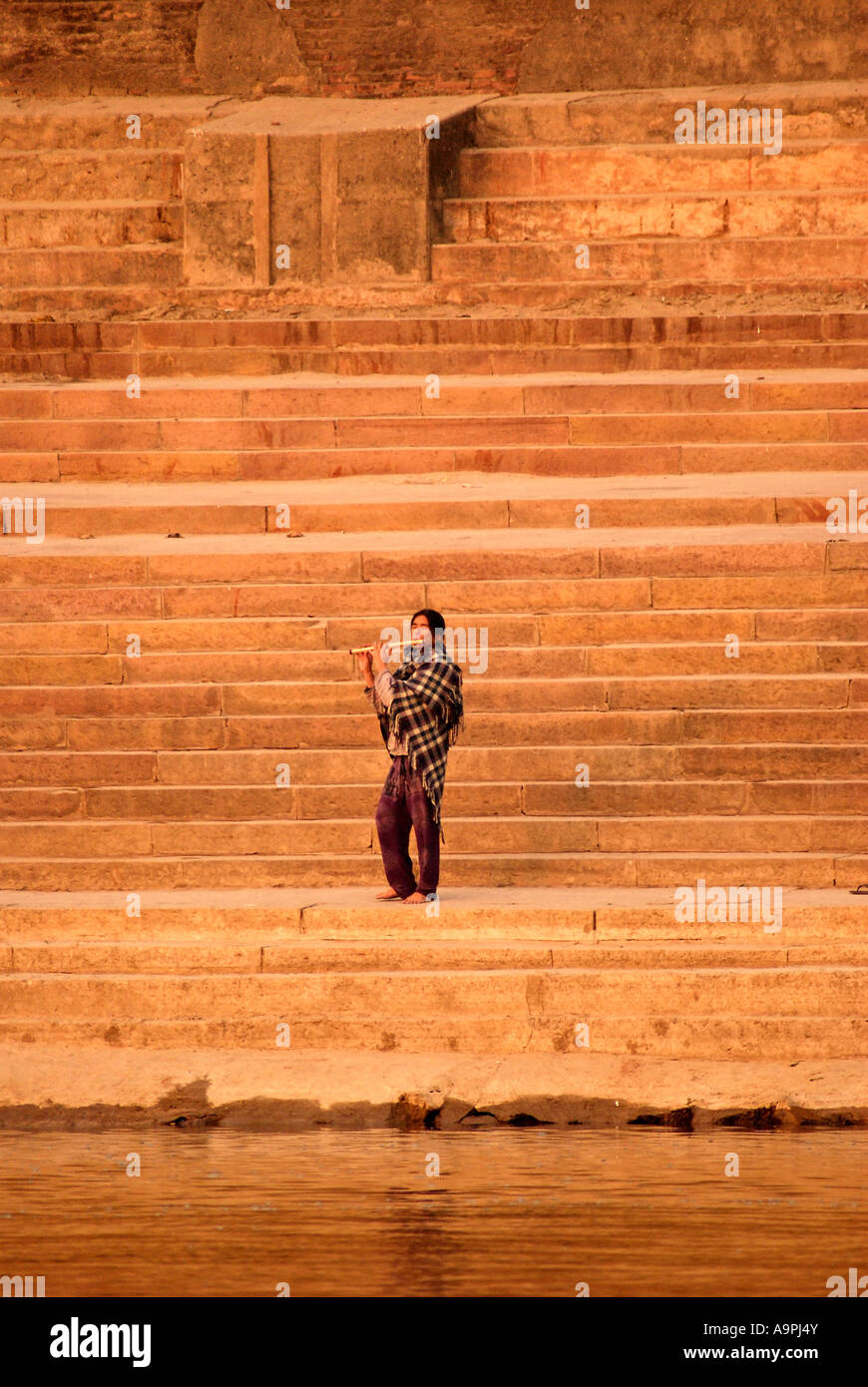 L'uomo la riproduzione di flauto sui Ghat passi, rive del Gange fiume, Varnasi, India Foto Stock