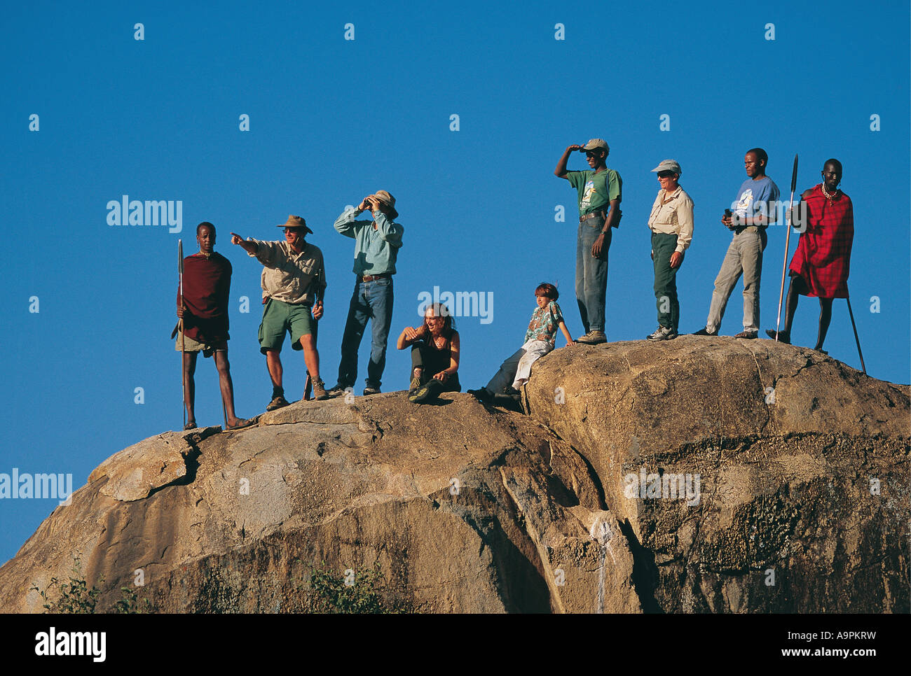 Gruppo di turisti con la loro africani e Maasai guide su un gioco a piedi Parco Nazionale del Serengeti Tanzania Foto Stock