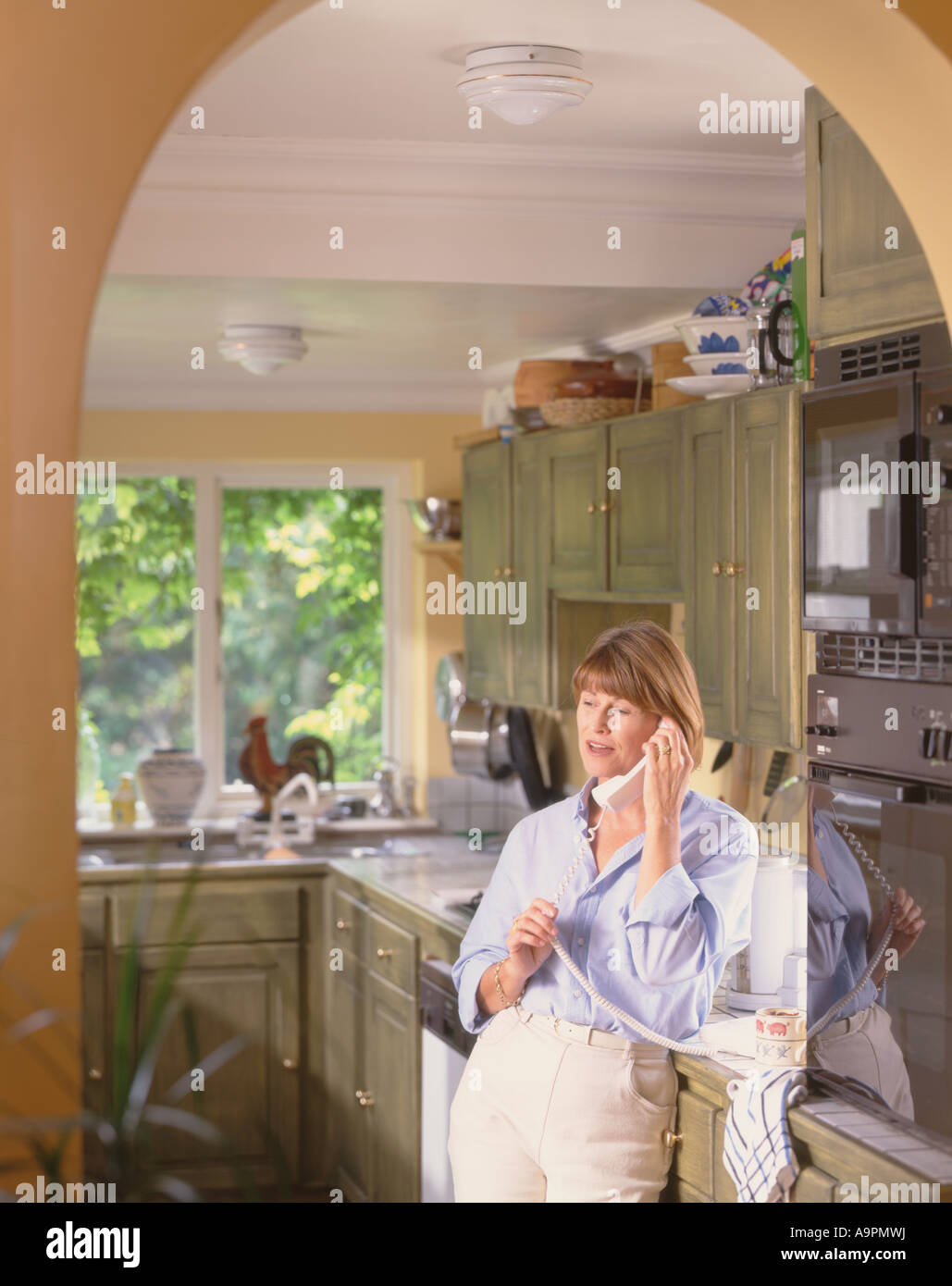 La donna in cucina utilizzando il telefono Foto Stock