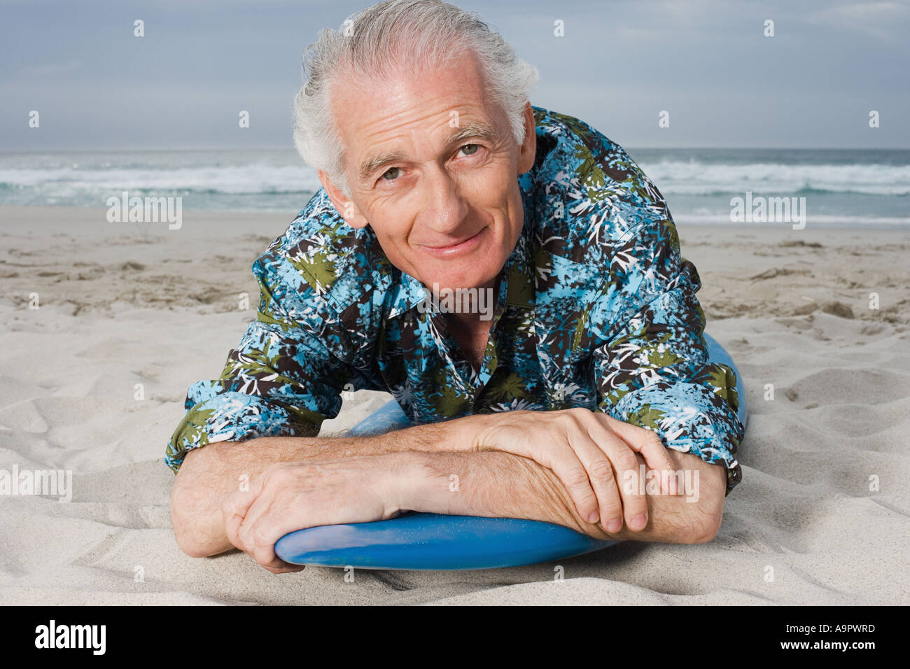 Senior uomo disteso sulla tavola da surf Foto Stock