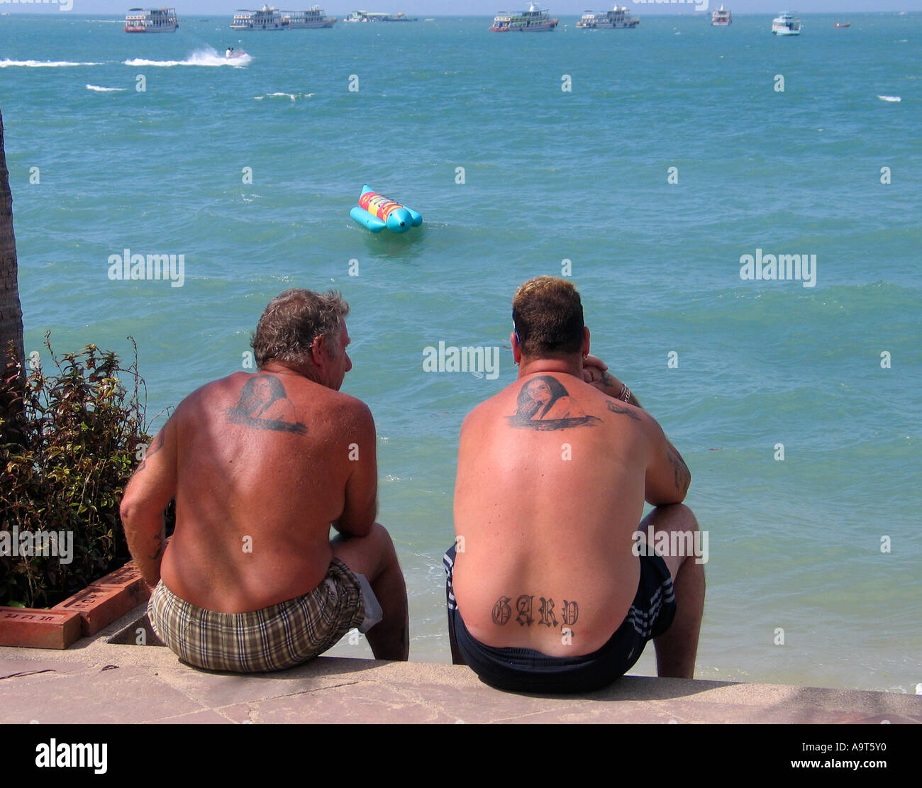 Due singoli maschi con tatuaggi simili godendo il sole Foto Stock