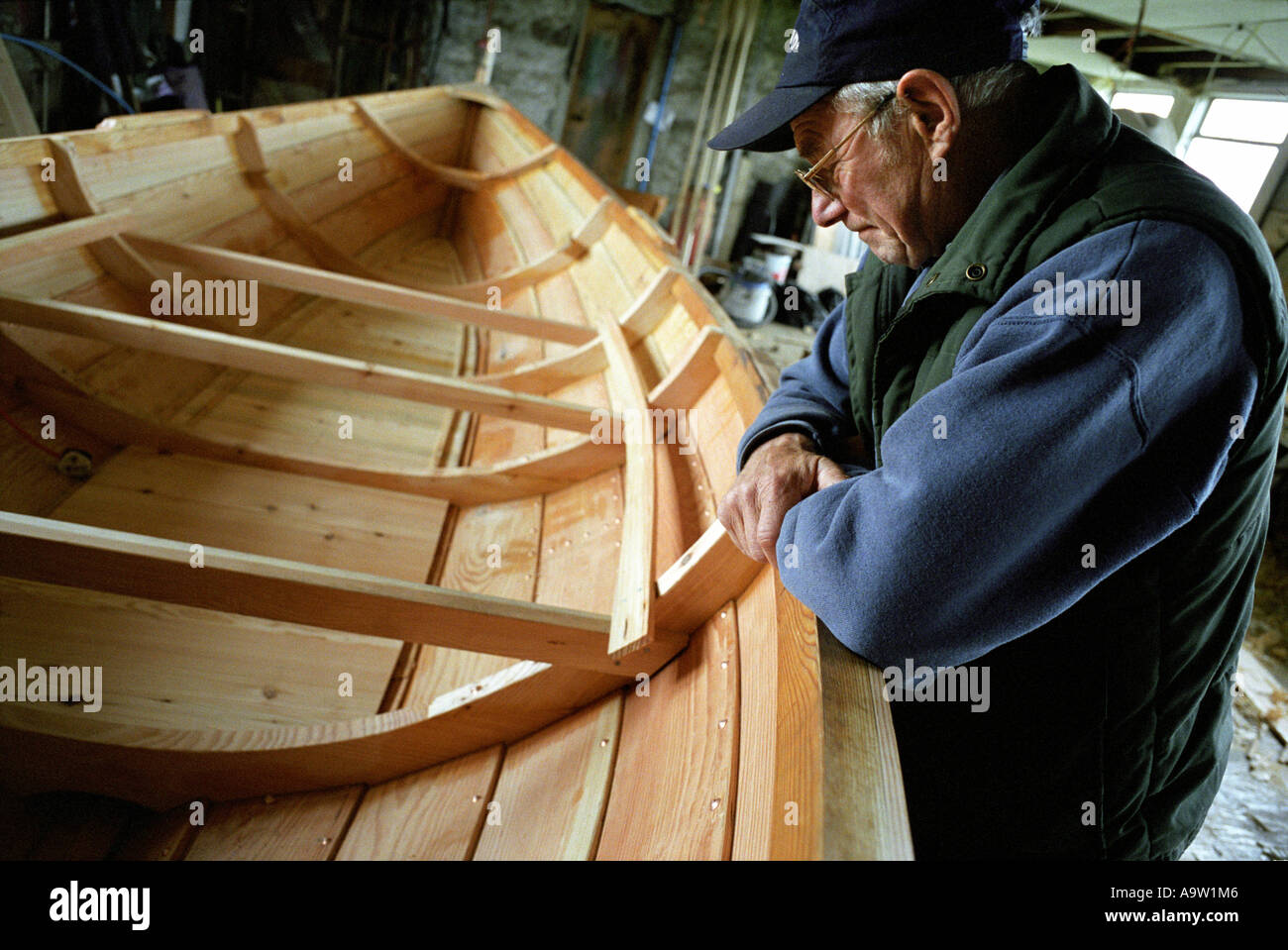 Un boatbuilder Shetland guarda oltre la barca di legno tradizionale, sapere come un 'yoal', che egli sta lavorando a. Foto Stock