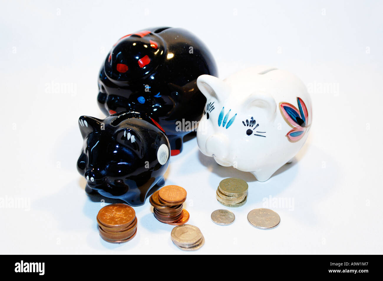 Tre macchiato il salvadanaio suini circondato da monete Foto Stock