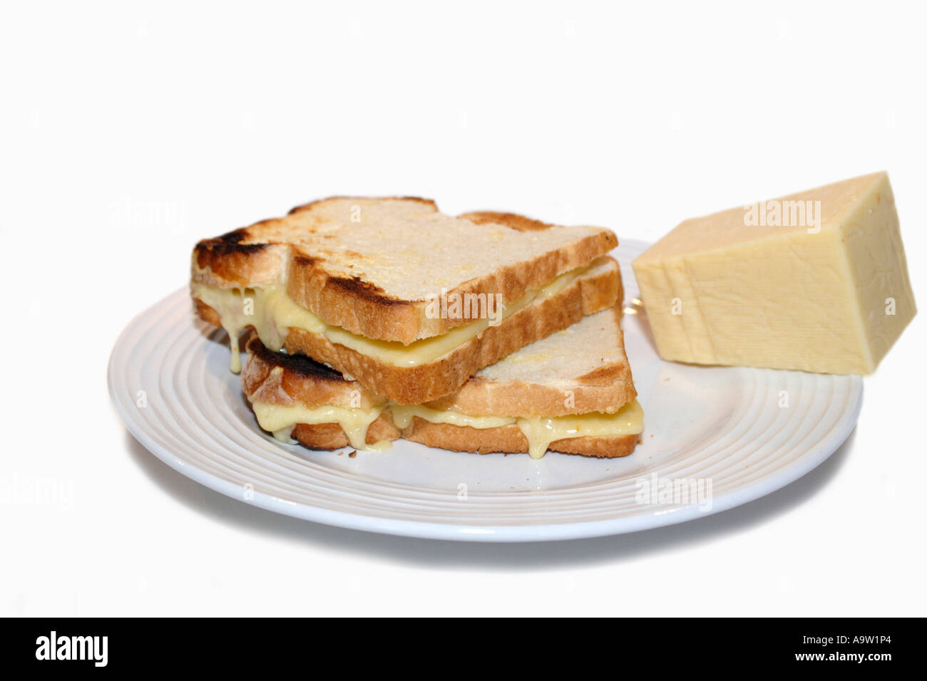 Tostato formaggio cheddar snadwich con formaggio liquefatto trasudamento e un blocco di formaggio solido in background Foto Stock
