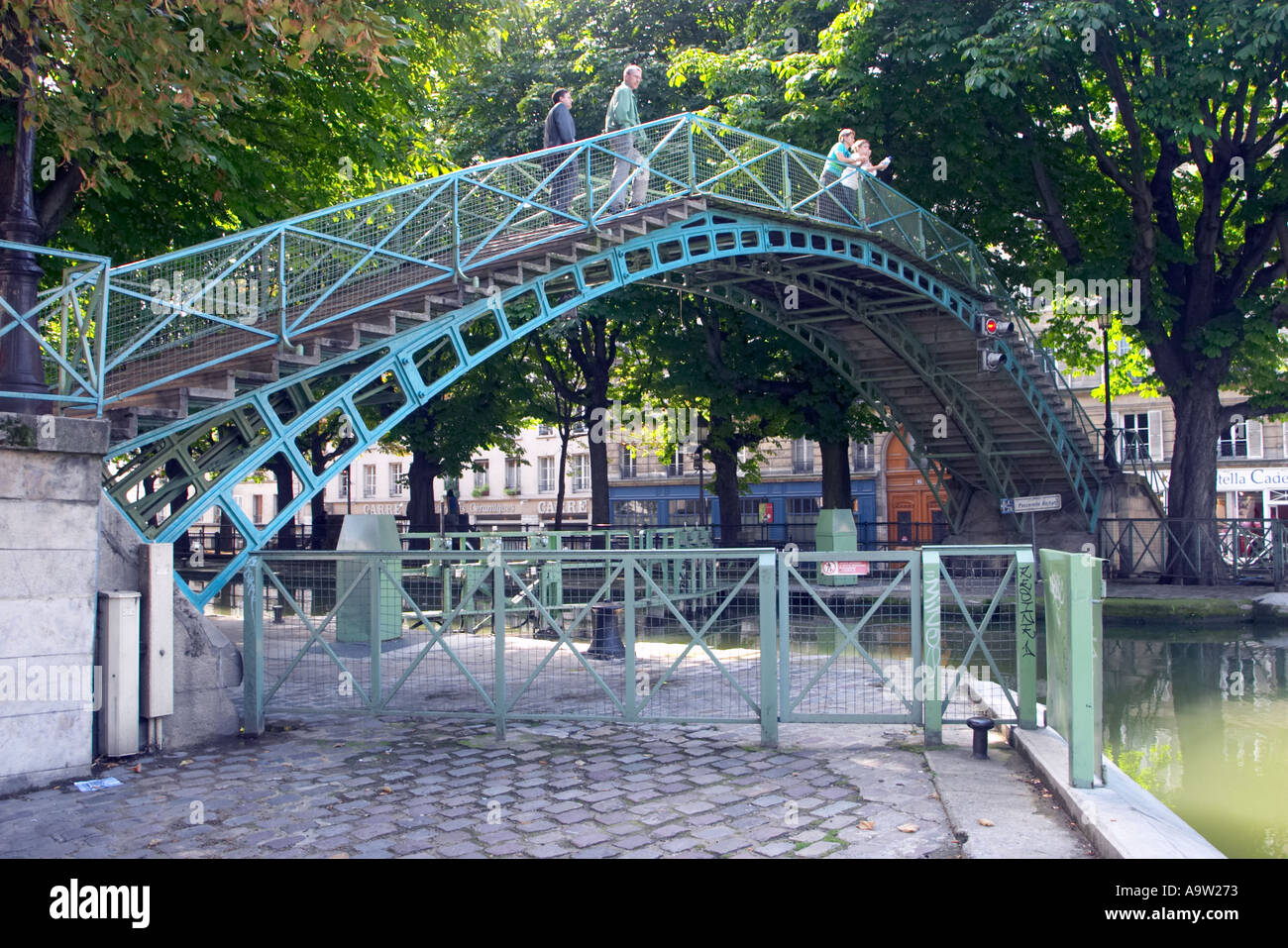 I turisti si godono una passeggiata attraverso la pittoresca Passerelle Bichat, una passerella in metallo che attraversa il Canal Saint-Martin a Parigi, in Francia Foto Stock