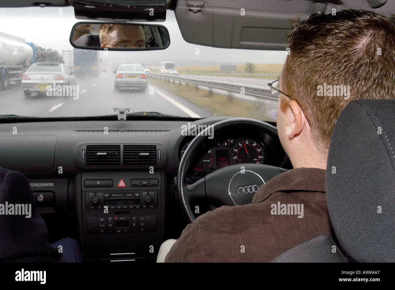 Uomo alla guida in autostrada visto dal sedile posteriore Foto Stock