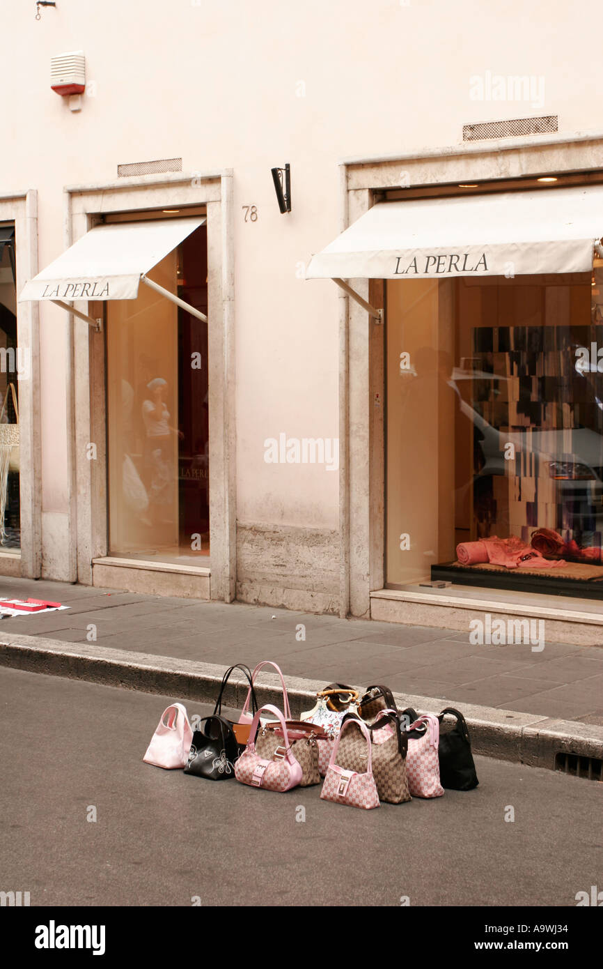 Contraffazione di designer borse in vendita al di fuori del La Perla shop a Roma Italia Foto Stock