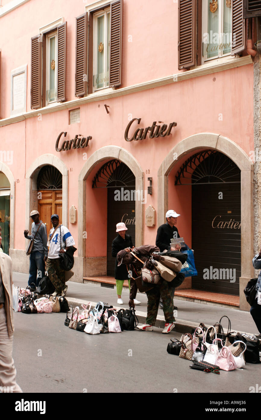 Contraffazione di fake designer borsette in vendita al di fuori del negozio  di Cartier a Roma Italia Foto stock - Alamy