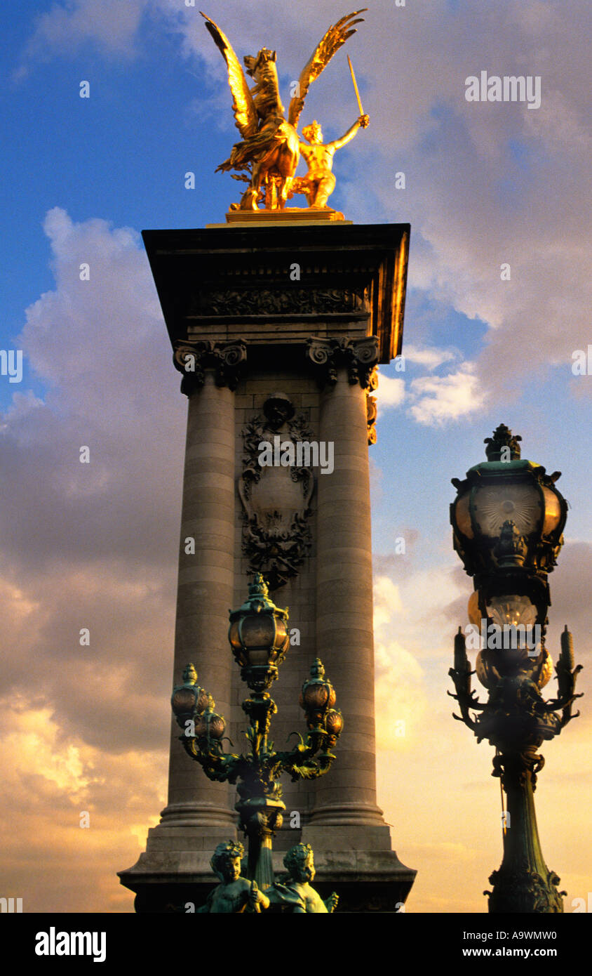 Francia Parigi Pont Alexandre III al tramonto nuvole e cielo drammatico. Luci di strada Art Nouveau e ponte in stile Beaux-Arts. Statua d'oro di Pegaso. Tramonto Foto Stock
