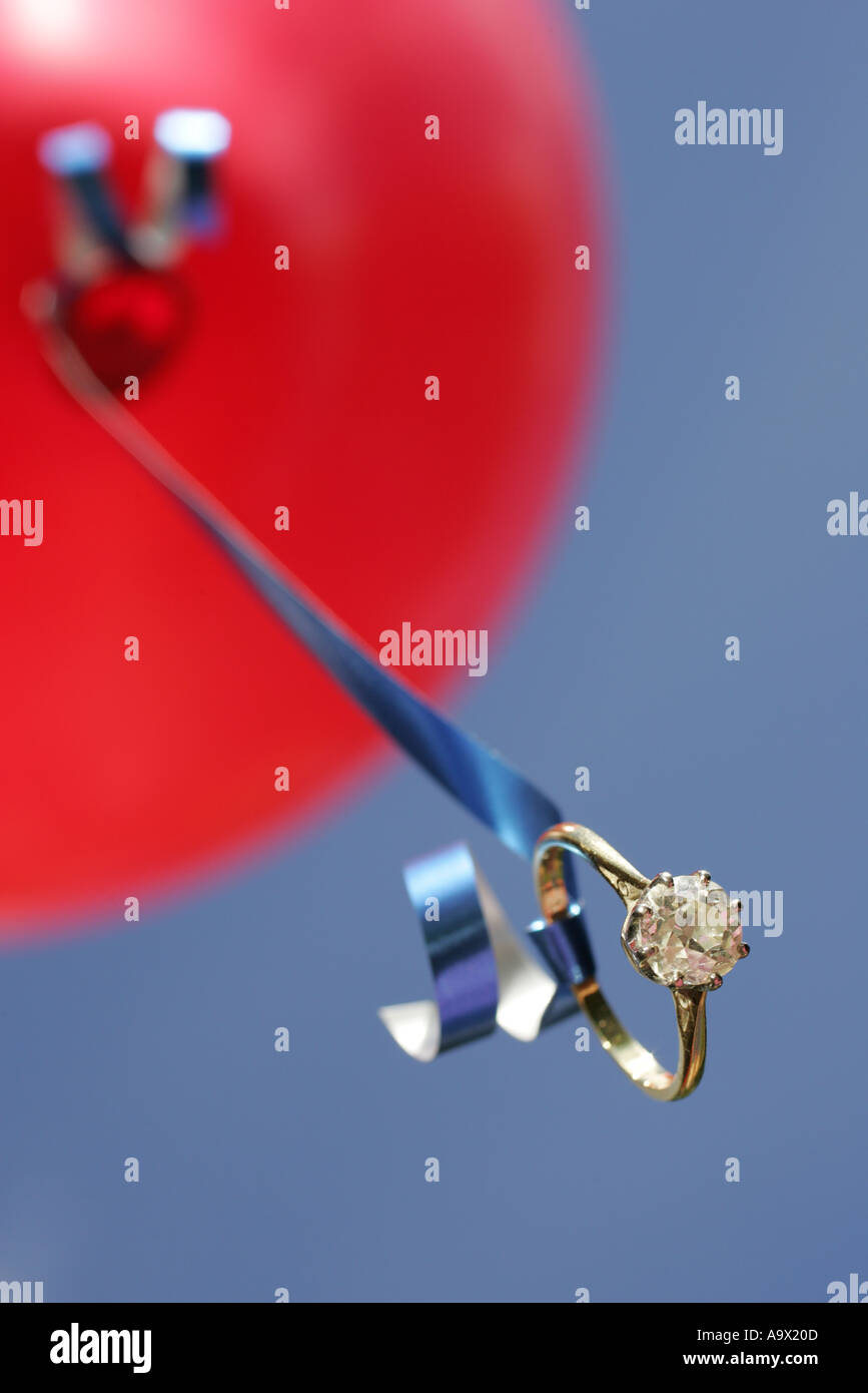 Solitaire anello di fidanzamento attaccato al nastro di un palloncino rosso a basso angolo di visione da vicino Foto Stock