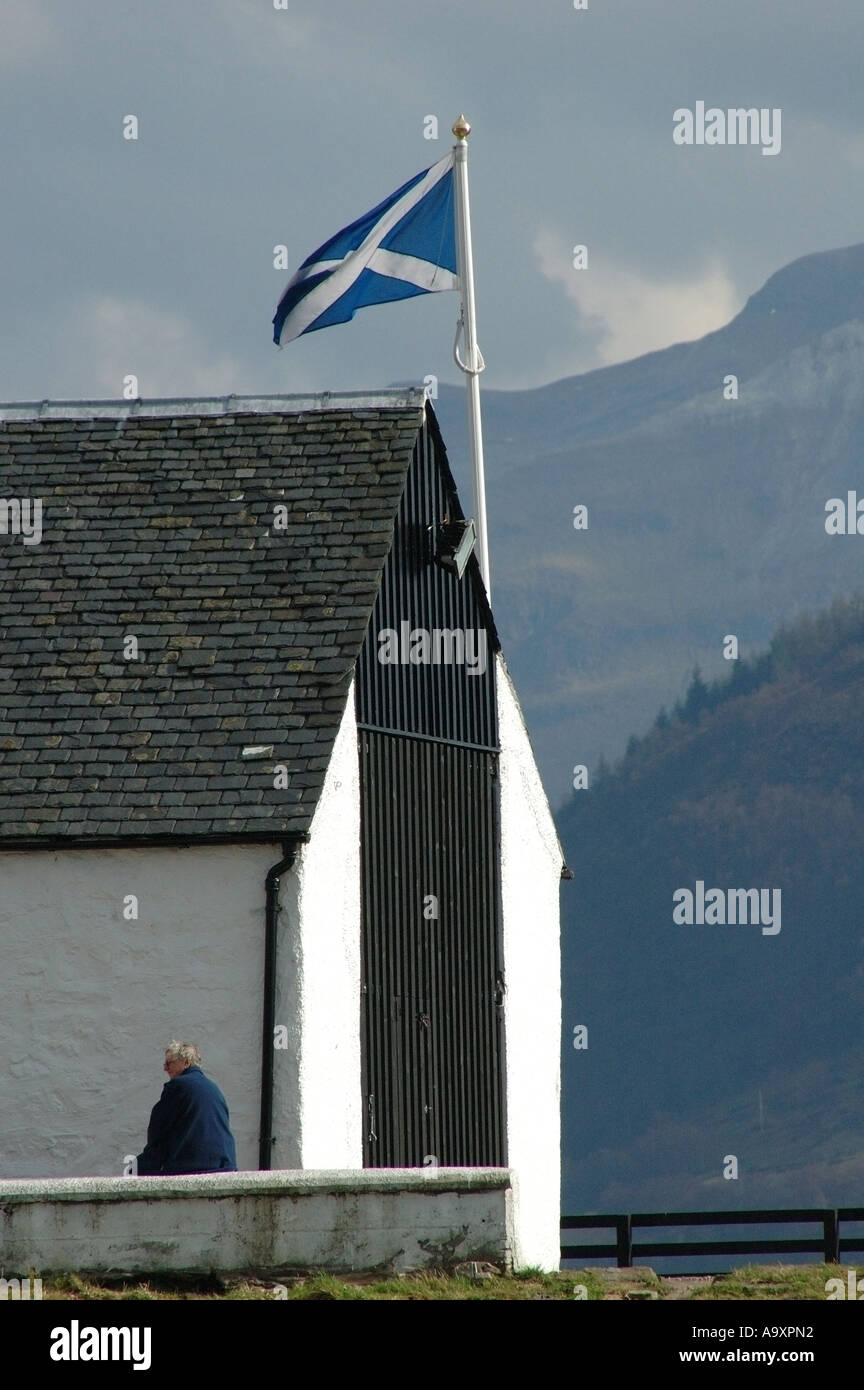 La figura seduta da edificio bianco con bandiera scozzese battenti a Corpach, Highlands scozzesi, R.U. Foto Stock