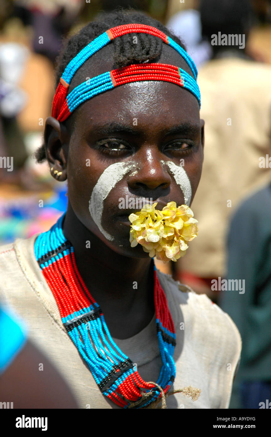 Giovane con un fiore in bocca e colorata collana e testa adorments mercato di Keyafer Etiopia Foto Stock