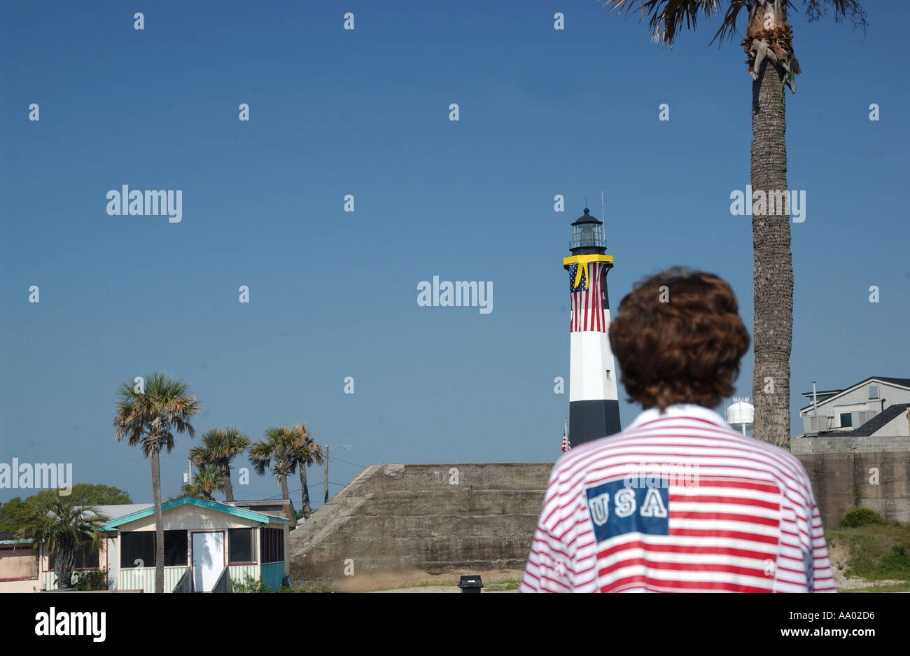 Una donna che indossa una camicia bandiera americana guarda l'iconico faro di Tybee Island, Savannah, Georgia, USA. Foto Stock