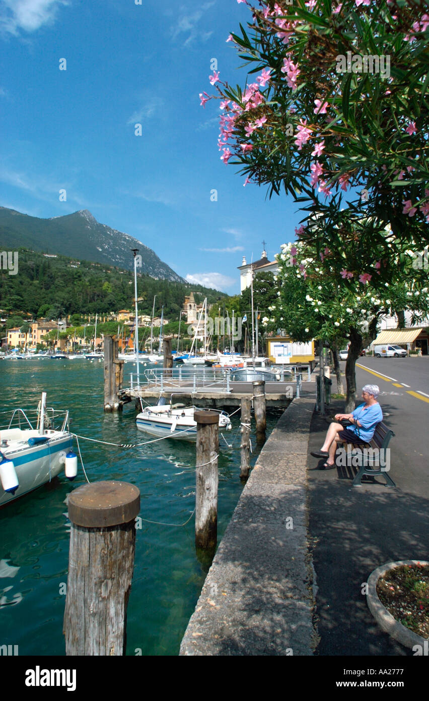 Donna seduta su una panchina dal porto di Maderno, Lago di Garda, Italia Foto Stock