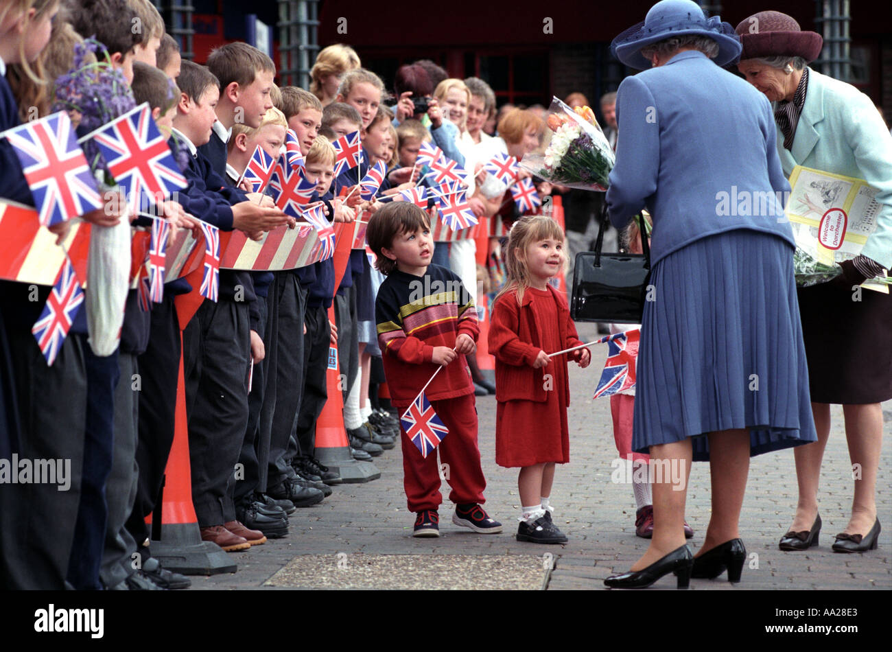 I bambini guardano su con stupore la Regina Elisabetta II durante una visita a suo figlio s Poundbury progetto di villaggio Foto Stock