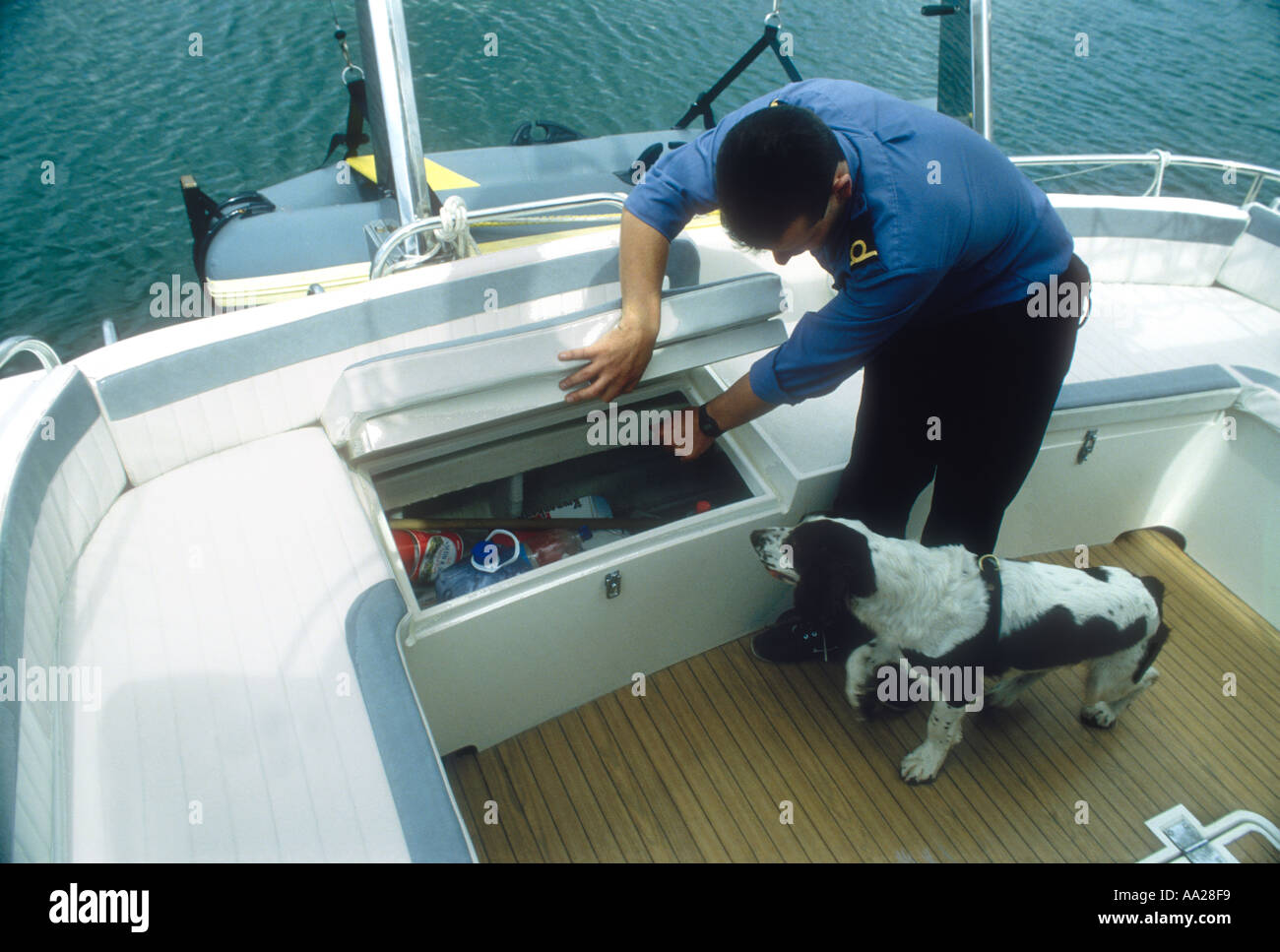 Una delle dogane e accise ufficiale con uno sniffer cane cerca un motor yacht per farmaci nascosti Poole Dorset England Regno Unito Foto Stock