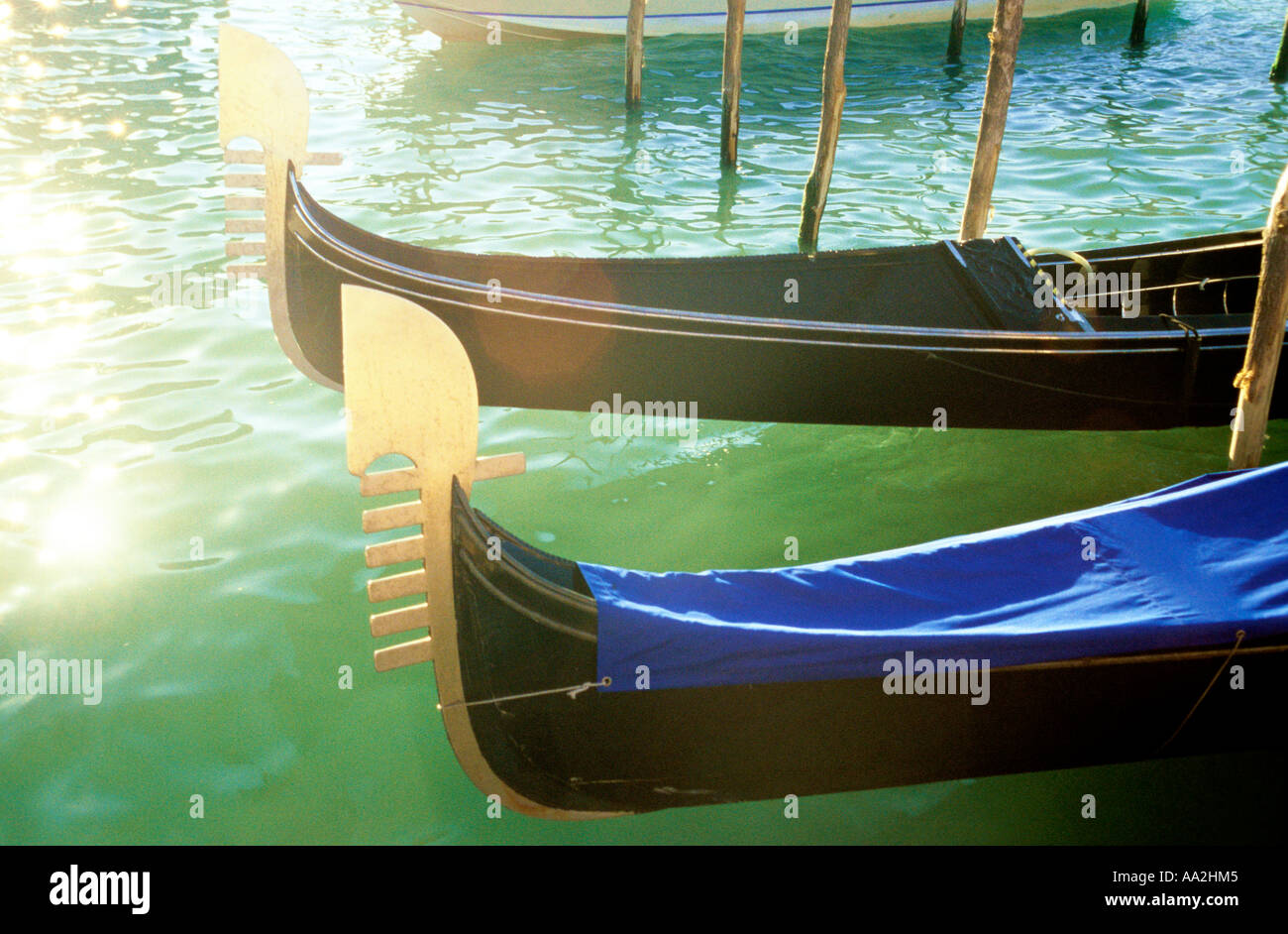 L'Italia, Venezia, gondole di sole sulla superficie di acqua Canale Grande Grand Canal, scolpiti prows delle gondole attraccate da canal Foto Stock