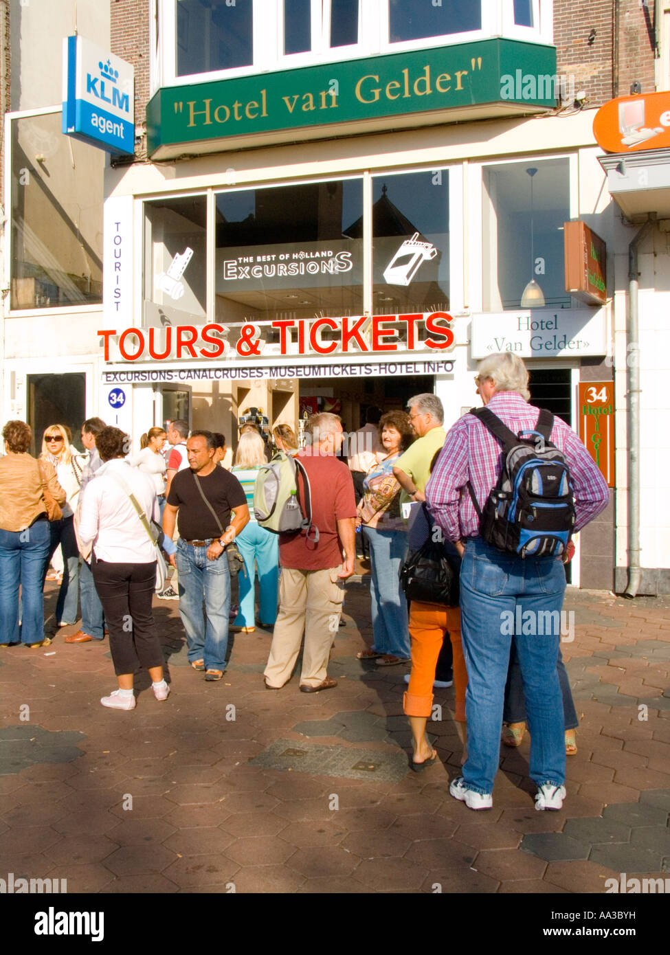 I turisti ed i visitatori di attendere al di fuori ufficio biglietti per unire ogni giorno Coach tours Damrak Amsterdam Paesi Bassi Foto Stock