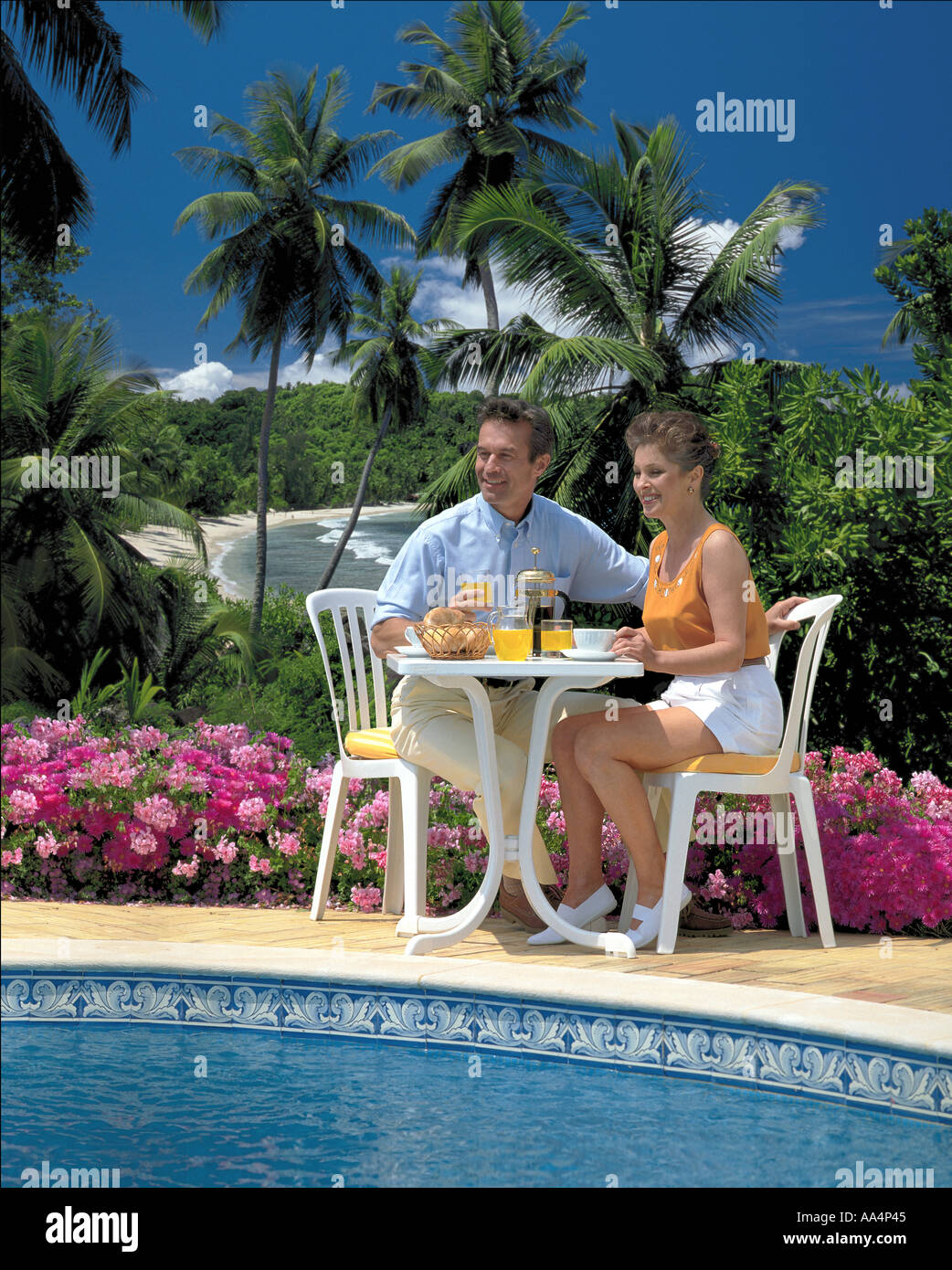 Paio di bere succo di frutta a bordo piscina in una posizione tropicale Foto Stock