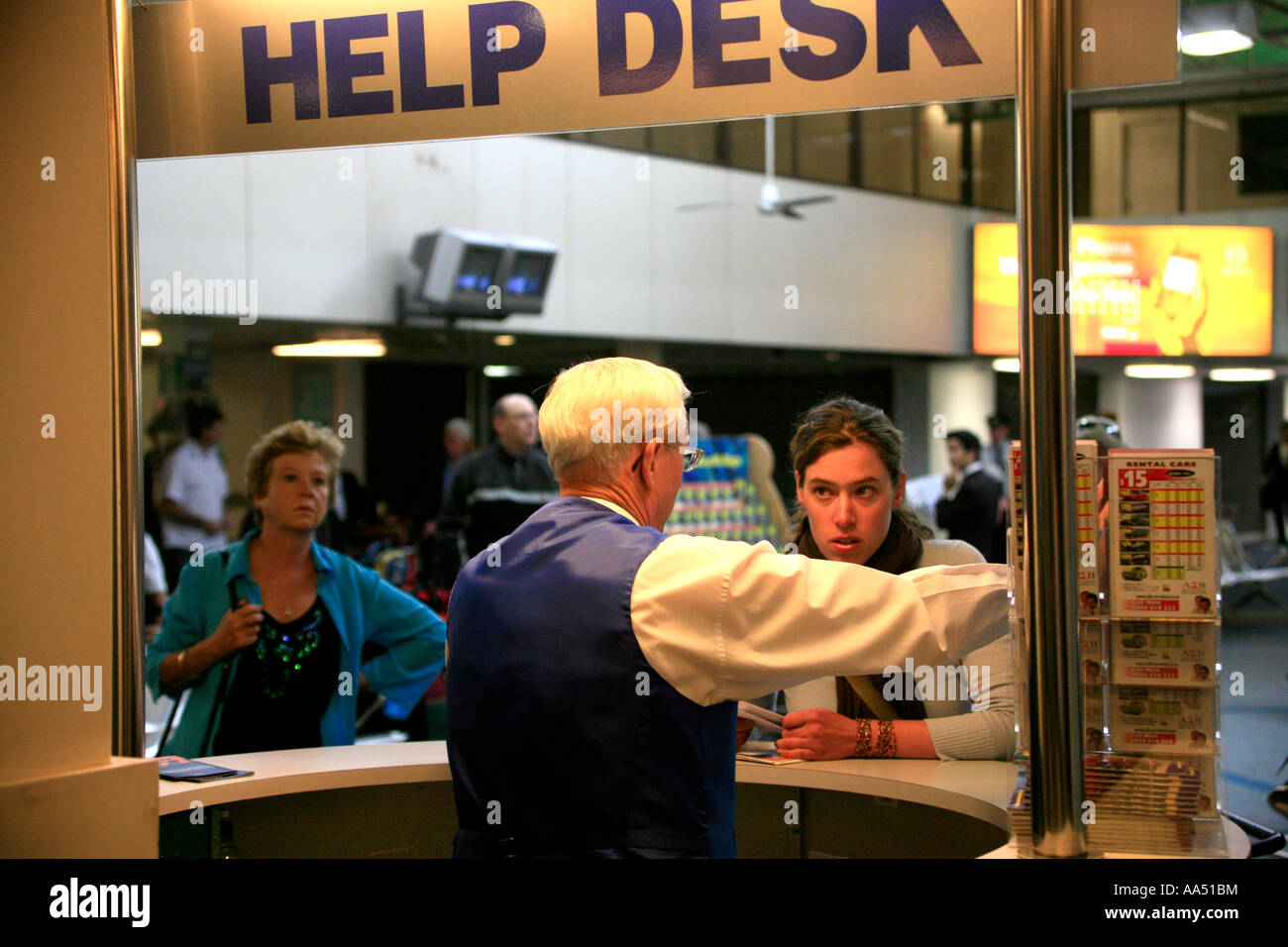 Un uomo anziano dà indicazioni come una giovane donna ascolta su un Help Desk presso il terminal dei voli interni in aeroporto di Auckland Nuova Zelanda Foto Stock