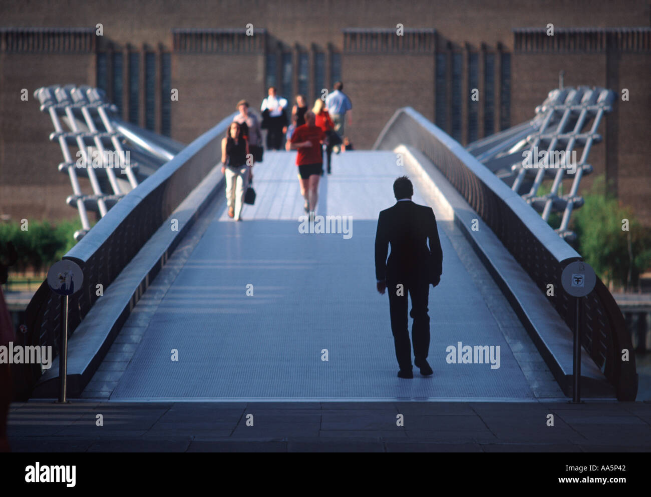 Singolo imprenditore della silhouette e pendolari crossing Millennium Bridge con la Tate Modern Gallery di distanza, Bankside, Londra Foto Stock