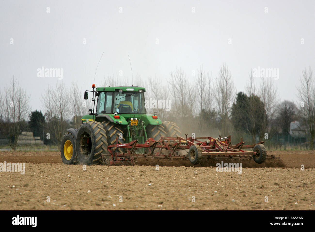 Verde di grandi dimensioni trattore agricolo tirando un aratro moderno attraverso un Norfolk farm field East Anglia England Regno Unito GB Gran Bretagna Foto Stock
