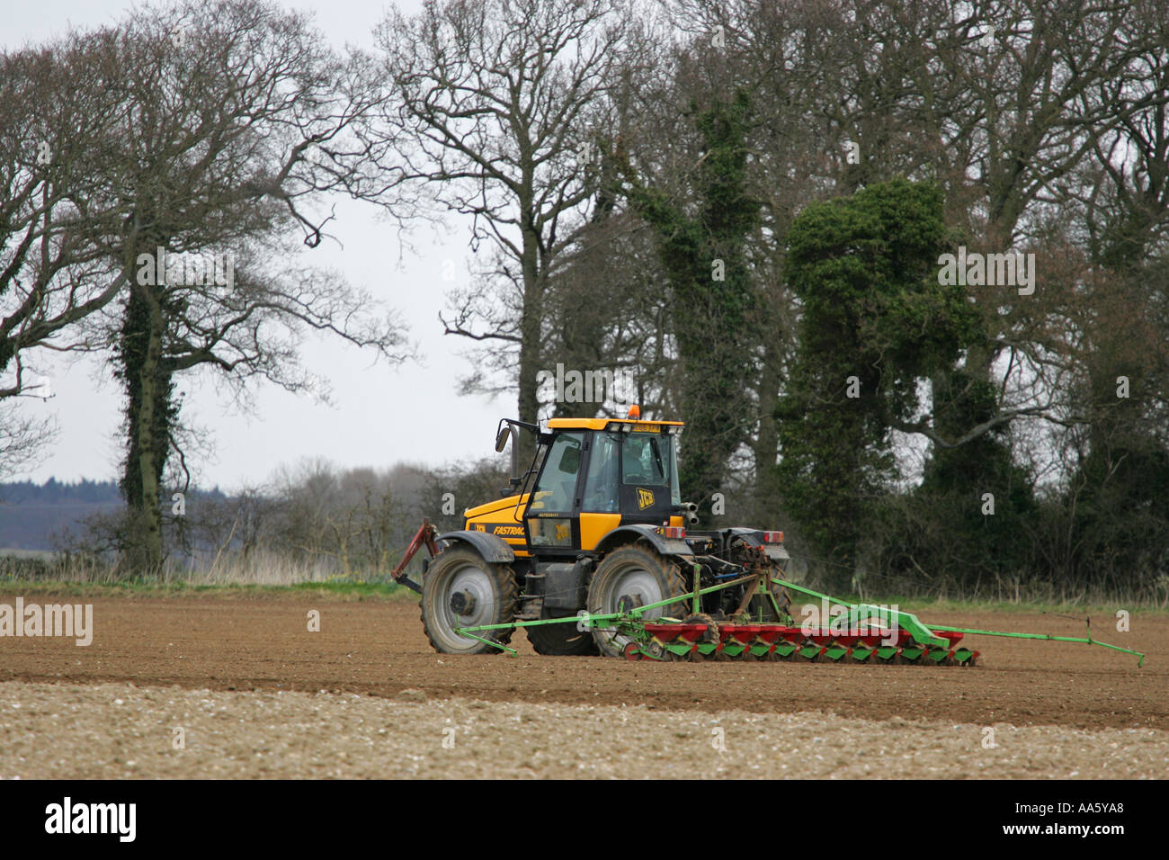 Grande trattore agricolo tirando un aratro moderno attraverso un Norfolk farm field East Anglia England Regno Unito GB Gran Bretagna Foto Stock