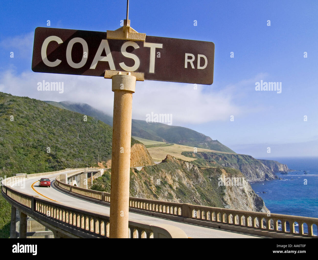 COAST ROAD SEGNO CALIFORNIA BIXBY BRIDGE BIG SUR DRIVE VACANZA SUN Coast Road segno, auto rossa che attraversa Bixby Bridge a Big sur, Monterey, California Stati Uniti Foto Stock