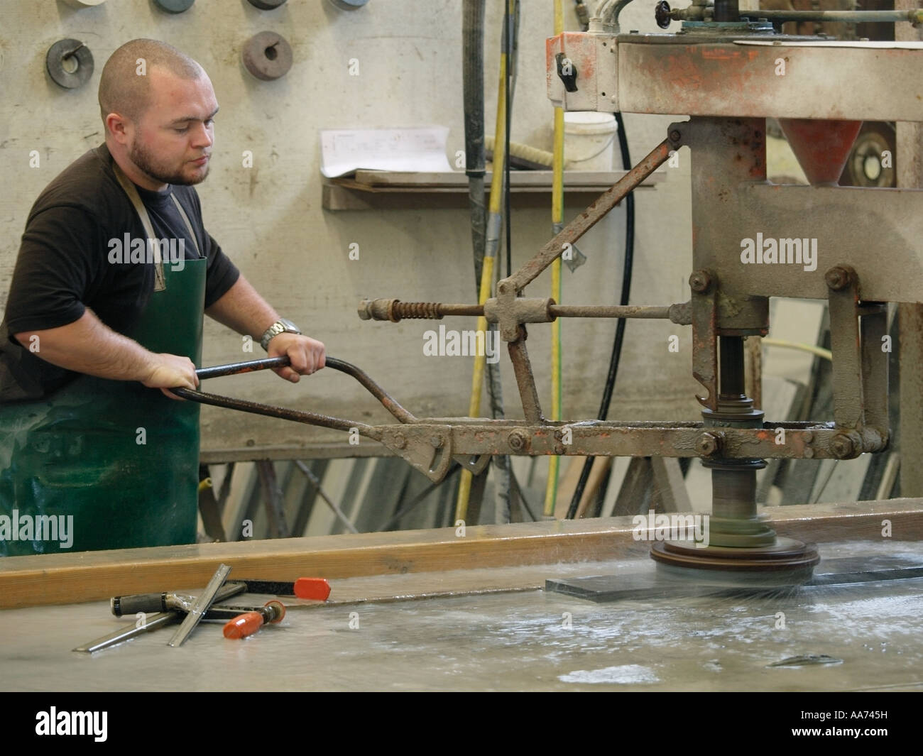 Lavoratore utilizzando una grande acqua raffreddata pneumatico macchina di lucidatura per la lucidatura di un lastra di marmo Foto Stock