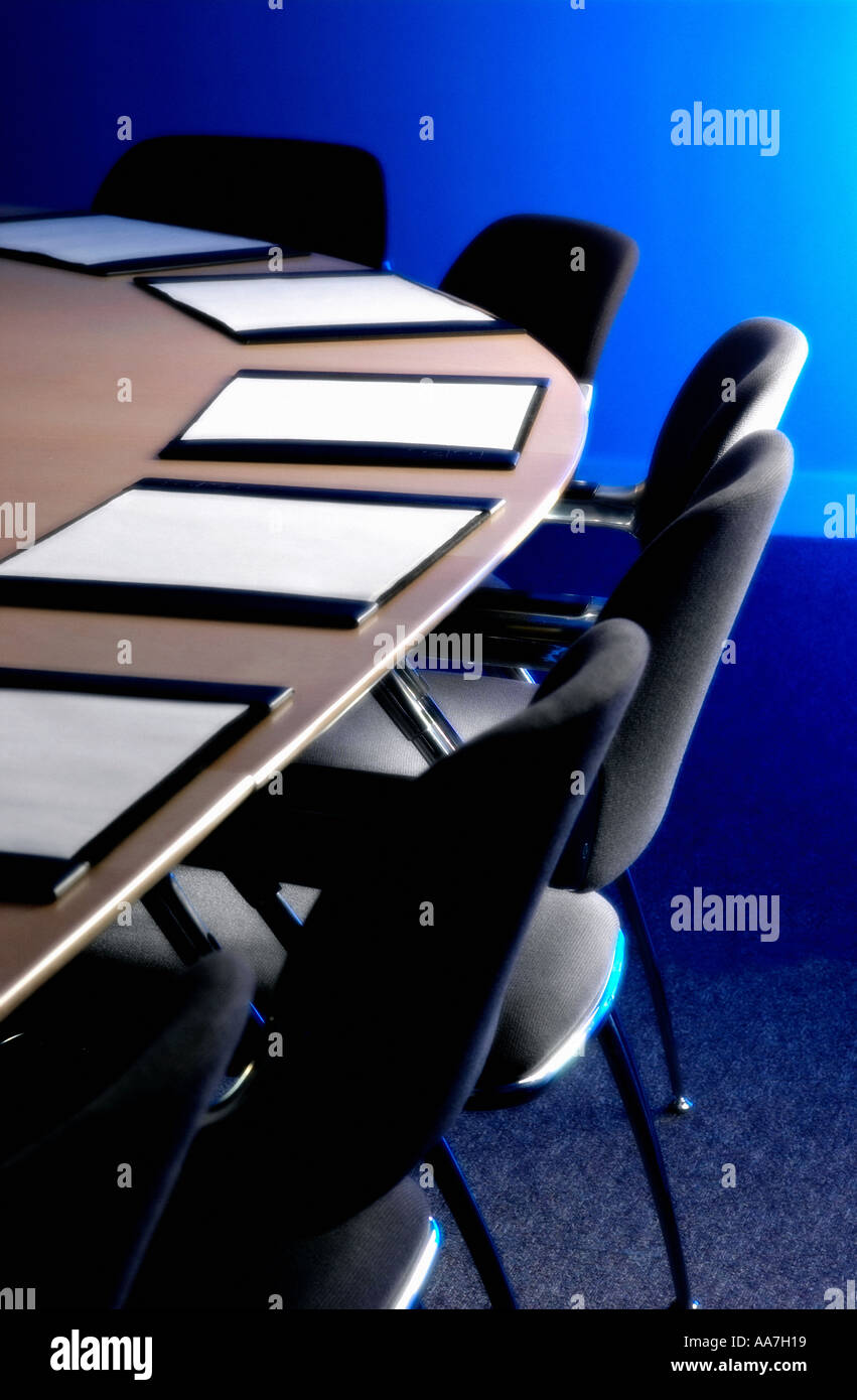 Sedie nere e blotter pad in pelle su una scrivania in legno in una sala riunioni vuota Foto Stock
