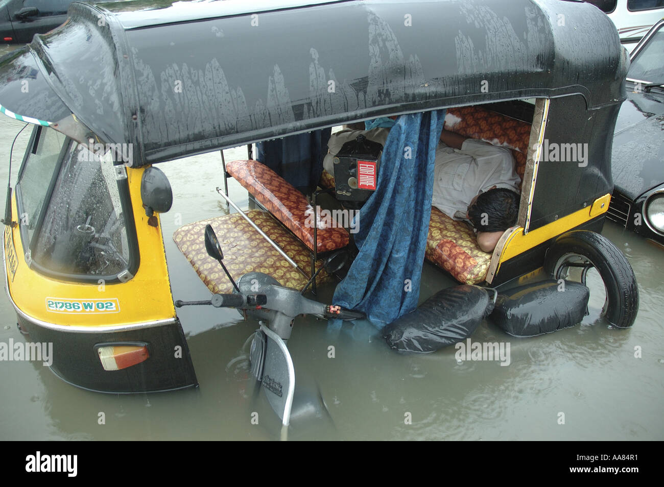 Inondazioni dovute a piogge monsoniche mostra driver dormire in auto rickshaw in acqua allagata Mumbai India Foto Stock