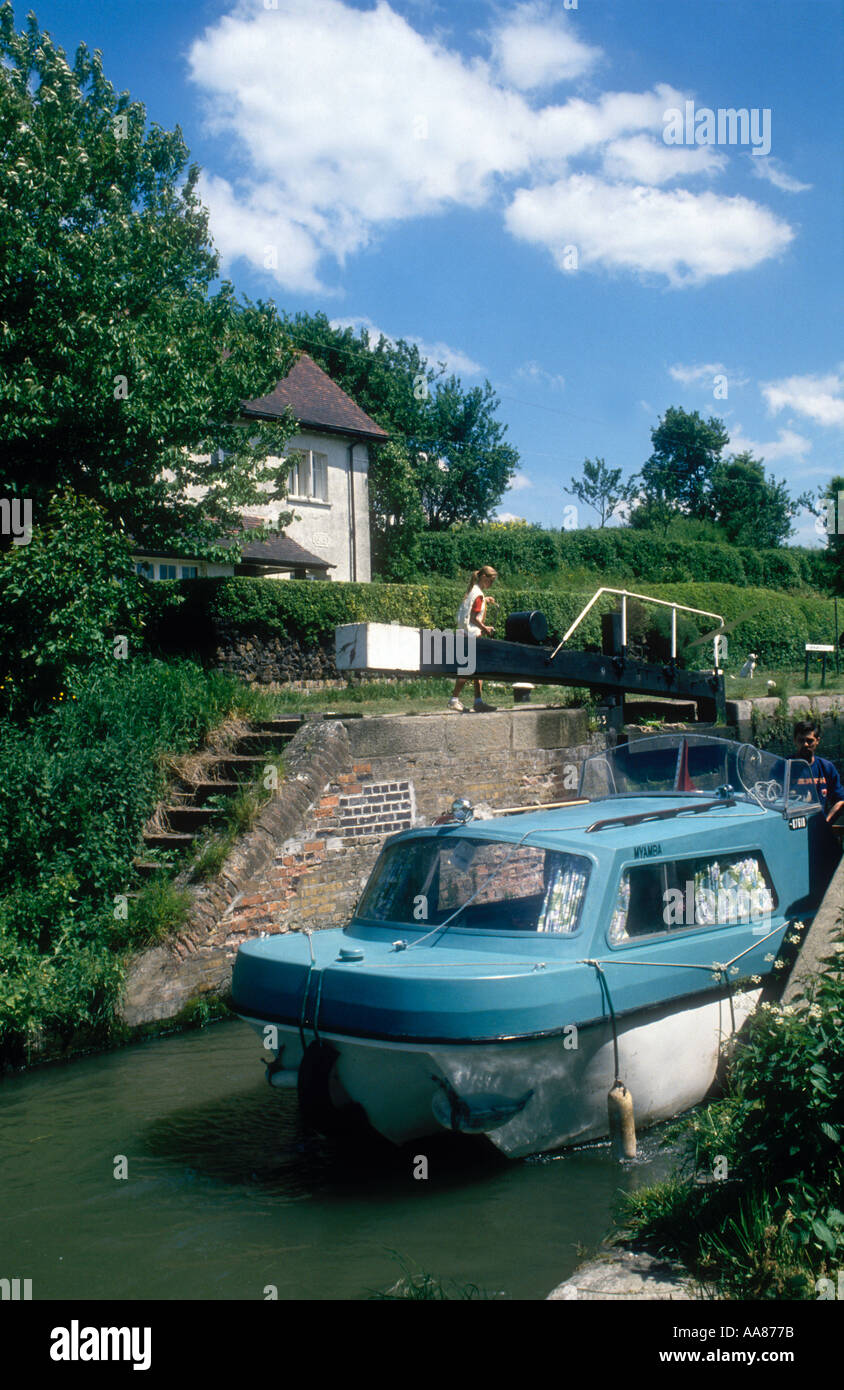 Una piccola barca a motore passa attraverso un blocco sul Grand Union Canal a Marsworth nel Buckinghamshire England Regno Unito Foto Stock