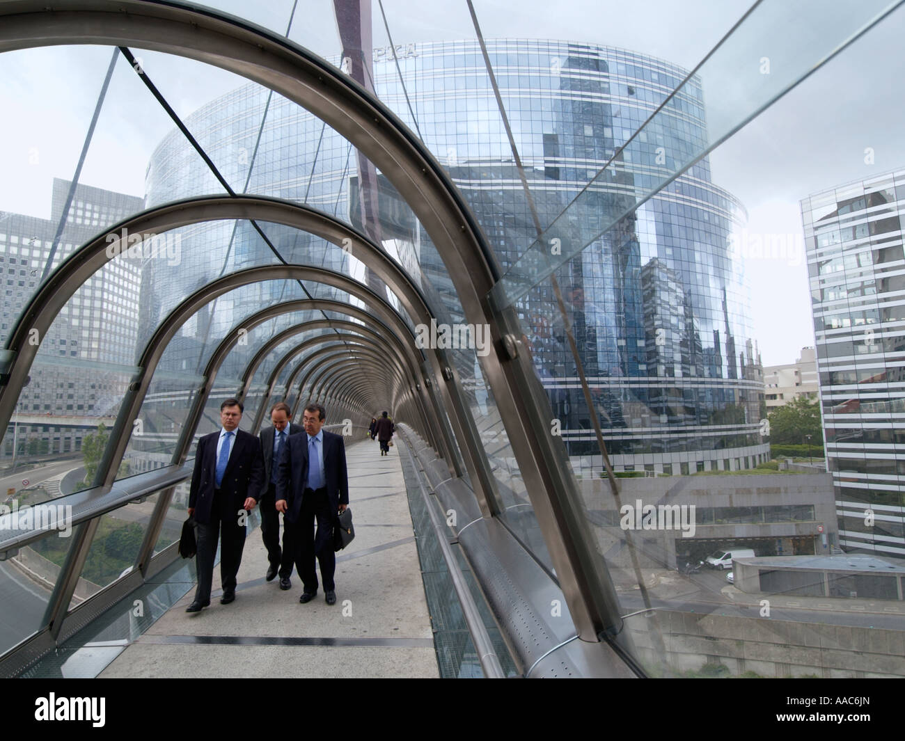Tre uomini di affari a piedi su vetro ponte coperto a La Defense Parigi Francia centro finanziario Foto Stock